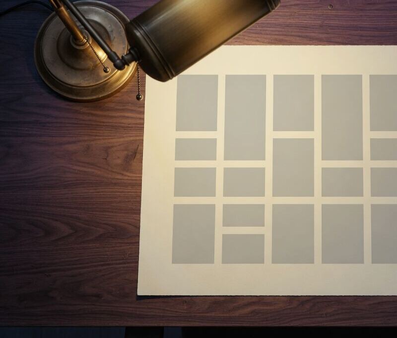 A desk lamp over a layout sheet of empty text blocks.